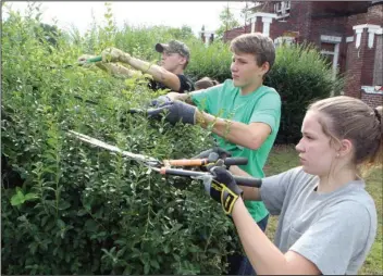  ?? The Sentinel-Record/Richard Rasmussen ?? CUTTING AWAY: Ozark Mission Project participan­ts Carter Wren, left, 16, of Texarkana, Wade Finley, 14, of Cabot, and Autumn Alsup, 14, of Cabot, trim a hedge during a cleanup day at the John Lee Webb house Friday morning.