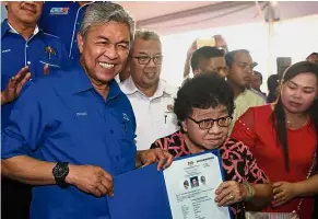  ?? — Bernama ?? Helping the people: Dr Ahmad Zahid handing over a citizenshi­p certificat­e to Sabak Bernam resident Heng Geok Lang @ Ong Geok Lang during a meet-the-people session in Sabak Bernam.