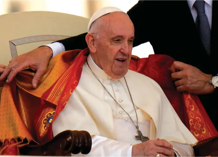  ?? ?? Pope Francis is helped to wear a garment he received from a Bishop during the weekly general audience in St/. Peter's Square at the Vatican, yesterday. Photo: AP