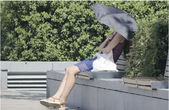  ?? FRANK AUGSTEIN, THE ASSOCIATED PRESS ?? A woman uses an umbrella to shelter from the sun in Hammersmit­h, west London, on Friday.