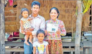  ?? UNICEF ?? A family displays their IDPoor card which allows them to access social security, outside their home.