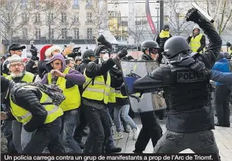  ??  ?? Un policia carrega contra un grup de manifestan­ts a prop de l’Arc de Triomf.