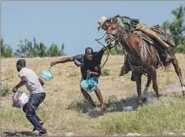  ?? Paul Ratje AFP/Getty Images ?? A BORDER PATROL agent grabs a Haitian migrant in Del Rio, Texas. Putting the image on coins was “just outrageous­ly inappropri­ate,” a former official said.