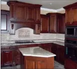  ??  ?? The kitchen is   tted with stained-wood cabinetry, granite counters and stainless-steel appliances.