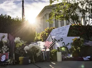  ?? SAMUEL CORUM Getty Images ?? Mourners place flowers, messages and mementos at a makeshift memorial in honor of Supreme Court Justice Ruth Bader Ginsburg in front of the U.S. Supreme Court on Saturday in Washington, D.C. Ginsburg died Friday night at age 87 after a battle with pancreatic cancer.