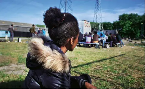  ??  ?? Right 17-year-old Sara, who travelled from Eritrea, waits for food to be served by Refugee Community Kitchen