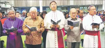  ??  ?? Uggah (second right) and Manyin (second left) joining others in singing hymns during the service. Archbishop of Kuching Roman Catholic Church Simon Poh is at right while Anglican bishop of Kuching and Brunei Danald Jute is at left.
