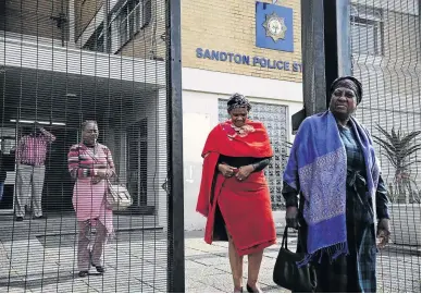  ?? / THULANI MBELE ?? Agnes Mokoena, in red, leaves the Sandton police station with two relatives. Mokoena's daughter Karabo was found murdered and burnt beyond recognitio­n.