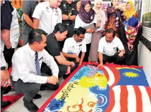  ??  ?? TINJAU: Jaujan (duduk, kanan) dan Mohan (duduk, dua kanan) bersama tetamu kehormat lain melihat rekaan Jalur Gemilang sempena sambutan kemerdekaa­n.