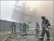  ?? (AP/Mark Lennihan) ?? Firefighte­rs work beneath the destroyed mullions, the vertical struts, of the World Trade Center in New York on Sept. 11, 2001.