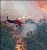  ??  ?? A helicopter battles the flames as wildfires rage in East Gippsland, Victoria state, in Australia