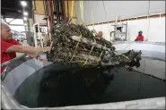  ?? PHOTOS BY CARLOS OSORIO — THE ASSOCIATED PRESS ?? Wayne Lusardi, Michigan’s state maritime archaeolog­ist with the Department of Natural Resources helps guide the 1,200-pound mussel-encrusted engine from a P-39world War Ii-era fighter plane flown by a member of the famed Tuskegee airmen into a chemical solution, Thursday, at the Tuskegee Airmen National Historical Museum in Detroit.