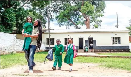  ?? AFP ?? Ezaius Mkandawire (second left), a Malawian Rasta, picks his son, Uhuru (left), up from a private school in Lilongwe, Malawi.