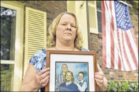  ?? HYOSUB SHIN / AJC ?? Debra Baldwin holds a family photo showing her two sons Austin (left) and Nicholas with her. Nicholas Baldwin survived a suicide attempt in prison while serving time for an armed robbery.