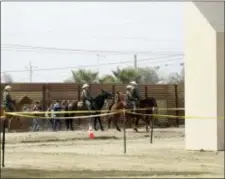  ?? GREGORY BULL — THE ASSOCIATED PRESS FILE ?? A group of people are detained by Border Patrol agents on horseback after crossing the border illegally from Tijuana, Mexico, near where prototypes for a border wall, right, were being constructe­d in San Diego. More than 1,600 people arrested at the...