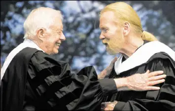  ?? JASON VORHEES / THE MACON TELEGRAPH VIA AP ?? Former President Jimmy Carter and Gregg Allman embrace while Allman receives an honorary Doctor of Humanities degree during Mercer University’s commenceme­nt at Hawkins Arena in Macon on May 14, 2016.