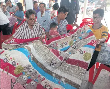  ?? TAWATCHAI KEMGUMNERD ?? Sing Buri residents show blankets they received from the Social Developmen­t and Human Security Ministry, telling them the high-priced blankets purchased for the poor turned out to be of low quality.