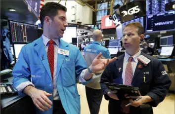  ?? Richard Drew/Associated Press ?? Specialist Thomas McArdle, left, and trader Robert Charmak work on the floor of the New York Stock Exchange on Wednesday. Stocks cinched their fourth gain in a row Wednesday.