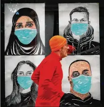  ?? ROBERT F. BUKATY/ASSOCIATED PRESS ?? A runner passes by a window displaying portraits of people wearing face coverings to help prevent the spread of the coronaviru­s in Lewiston, Maine. An alarming surge in COVID-19 infections is making federal, state and local officials push for more mask wearing.
