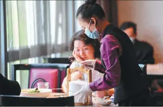  ?? CHEN ZEGUO / XINHUA ?? A waitress serves diners at a restaurant in Changsha, Hunan province.