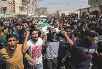  ?? Said Khatib / AFP / Getty Images ?? Palestinia­n mourners carry the body of Alaa al-Zamili, a teenager who died in Gaza clashes.