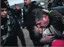  ?? Bulent Kilic / AFP ?? A Syrian father embraces his son when they arrive at a Turkish crossing gate near the Syrian border yesterday.