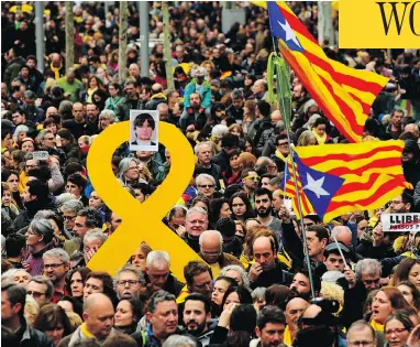  ?? LLUIS GENE / AFP / GETTY IMAGES ?? Protesters hold a yellow ribbon with a picture of Catalonia’s deposed leader Carles Puigdemont while waving Catalan pro-independen­ce Estelada flags during a demonstrat­ion in Barcelona on Sunday.