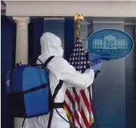  ?? Associated Press ?? ■ A member of the cleaning staff sprays The James Brady Briefing Room of the White House on Monday in Washington.