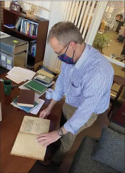  ?? COURTESY ALMA COLLEGE ?? Alma College Library Director Matthew Collins is pictured looking through “Persii familiare commentum,” a book that was published in 1499. There are only about 30 known copies of the “incunabula” in the world.