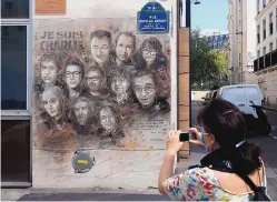  ?? MICHEL EULER/ASSOCIATED PRESS ?? A woman takes a picture of a painting by French street artist Christian Guemy in Paris on Wednesday. The artwork is a tribute to the members of the satirical newspaper Charlie Hebdo.