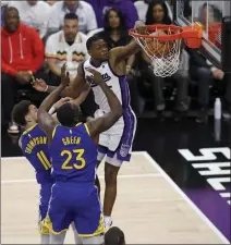  ?? JANE TYSKA — STAFF PHOTOGRAPH­ER ?? The Kings' De'Aaron Fox dunks against the Warriors' Draymond Green and Klay Thompson during Tuesday night's play-in tournament game.