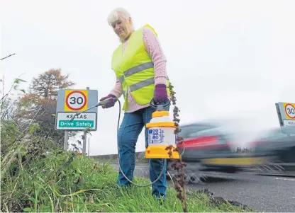  ?? Picture: Kim Cessford. ?? Marilyn Mauran sprays weeds to keep the speed limit signage visible.