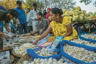  ?? ATUL LOKE/THE NEW YORK TIMES ?? A QR code perches atop a basket of garlic this week at a roadside produce vendor’s stall in Mumbai, India.