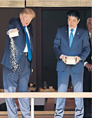  ??  ?? Mr Trump and Mr Abe appeared to lose patience while feeding koi carp in Tokyo, emptying their fish food cartons into the pond