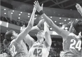  ?? JESSICA HILL/ASSOCIATED PRESS ?? Oregon's Oti Gildon, left, and Ruthy Hebard try to block a shot by Maryland's Brionna Jones during Saturday’s second half. Jones finished with 16 points and 15 rebounds.