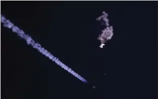  ?? CHAD FISH - VIA THE ASSOCIATED PRESS ?? The remnants of a large balloon drift above the Atlantic Ocean, just off the coast of South Carolina, with a fighter jet and its contrail below it Saturday. The U.S. says the Chinese balloon was part of an extensive surveillan­ce program.