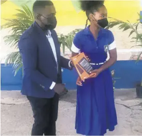  ?? ?? Andre Waugh (left), president of the Jonathan Grant Past Students’ Associatio­n, presents a tablet to a student of the school.