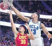  ?? Wally Skalij Los Angeles Times ?? IKE ANIGBOGU, a UCLA freshman, reaches over USC’s Elijah Stewart as the latter shoots in a Pac-12 Conference tournament game this month.