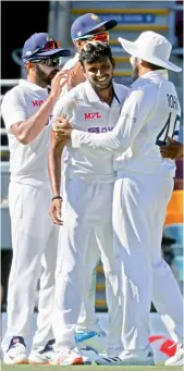  ?? — AFP ?? Thangarasu Natarajan (centre) celebrates the wicket of Marnus Labuschagn­e with teammates on Day One of the fourth Test at the Gabba in Brisbane.