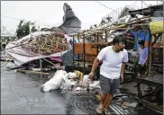  ?? AARON FAVILA / ASSOCIATED PRESS ?? A resident walks past damaged stalls at a public market in Tuguegarao city in Cagayan province, northeaste­rn Philippine­s on Saturday.