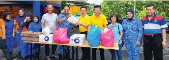  ?? — Photo by Peter Boon ?? Chieng (right) hands over the food packs to Azamsah, as others look on.