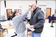  ??  ?? Volunteer Gerry Andrea of East Haven, left, checks the temperatur­e of Ron Parese of North Haven before he receives a dose of the Moderna COVID-19 vaccine at the East Haven Senior Center on Friday.
