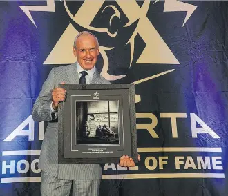  ?? LA MEDIA PHOTO ?? Ron MacLean holds up his plaque after being inducted into the Alberta Hockey Hall of Fame in Canmore. “It’s a nice moment, that your story — because we love stories —is preserved,” said MacLean.