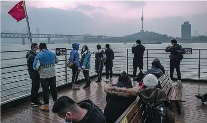  ?? EFE ?? Un grupo de pasajeros de un ferry cruzando ayer el río Yantze con Wuhan al fondo