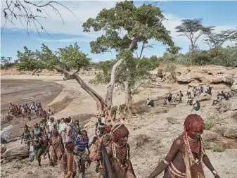  ??  ?? Hamar tribespeop­le and tourists head to a bull-jumping ceremony, a ritual initiation to manhood in Turmi, Ethiopia.