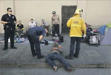  ?? Patrick T. Fallon For The Times ?? LOS ANGELES Fire Department paramedics and LAPD officers respond to a sick man on skid row. Though spice is often sold as fake marijuana, it can have much more powerful effects, including heart attacks, hallucinat­ions and seizures, said a county health official.