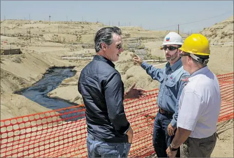  ?? Irfan Khan Los Angeles Times ?? GOV. GAVIN NEWSOM, left, is briefed in July on an oil spill in McKittrick, Calif., by Chevron’s Billy Lacobie, center, and state oil official Cameron Campbell. Newsom won praise Tuesday for ordering a scientific review of new plans for hydraulic fracturing by the oil industry.