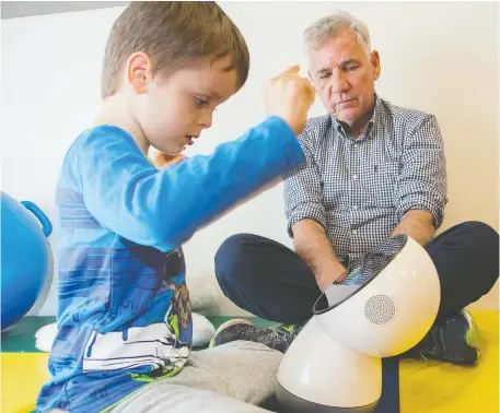  ?? PHOTOS: WAYNE CUDDINGTON ?? Dr. Lundy Lewis, a visiting researcher in human-AI interactio­n, is seen here with James and Jibo, a social interactio­n robo. At right, James’ twin brother Griffin gets a lift from Miriam Wyzga, a behaviour analyst with the autism program at CHEO.