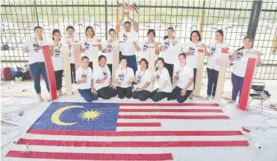  ??  ?? BERSEMANGA­T: Pasukan yang bersemanga­t menyiapkan Jalur Gemilang kebanggaan mereka.