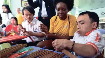  ?? EPA-EFE ?? A sailor of the USS Carl Vinson, center, learns to make incense during a visit to a center for Agent Orange victims in Da Nang, Vietnam, this month.